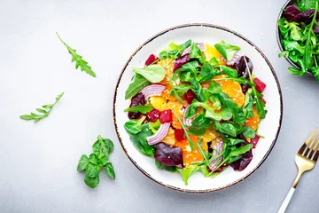 Poster Beet and orange healthy salad with arugula, lamb lettuce, red onion, walnut and tangerine, gray kitchen table. Fresh useful vegan dish for healthy eating © 5ph