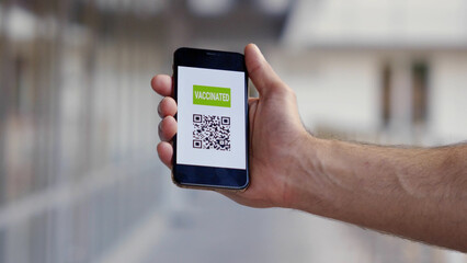 Male hand holding mobile phone with vaccinated qr-code