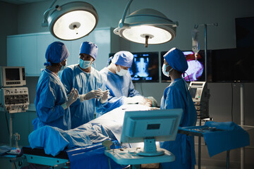 Doctor of or Surgeon, Medical team performing surgical operation in bright Modern operating room with art lighting and blue filter in hospital. Professional Medical Doctors Performing Surgery.