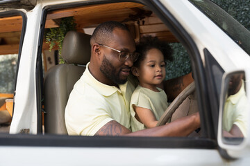 African American father and little daughter playing and driving together on holiday