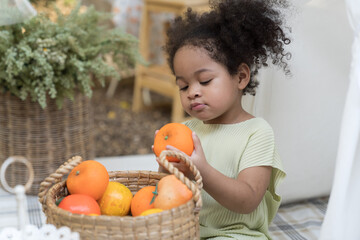 African American little girl playing alone with fruits in basket in the garden