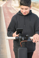 smiling young teenager riding an electric skateboard and using smart phone application E-Mobility urban leisure concept