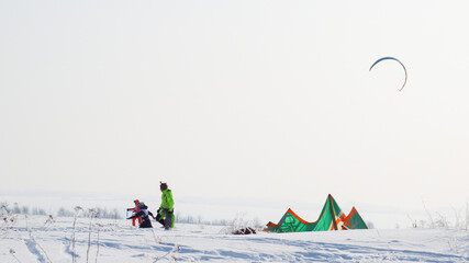 people kiting in winter in snowy terrain. snowkiting