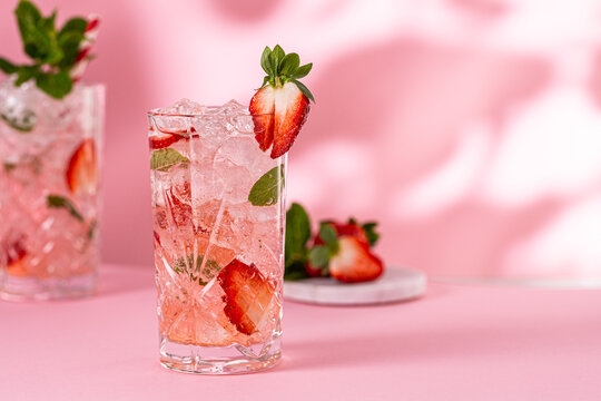 Healthy limonate with crushed ice, strawberry and mint on pinkbackground. Summer cold drink concept with copy space