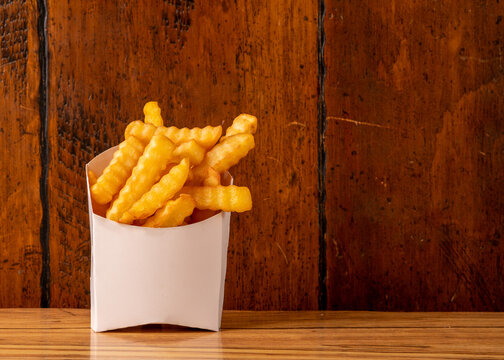 crinkle cut fries on a wood background