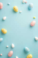 Easter atmosphere concept. Top view vertical photo of colorful easter eggs on isolated pastel blue background with copyspace in the middle