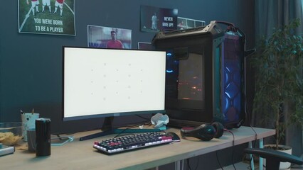 Full shot of professional gaming computer on desk with empty white screen, keyboard, mouse and headset, energy drink and bowl of chips beside. Suitable as copy space, chromakey template