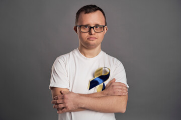 Portrait of man with down syndrome on gray background with yellow and blue bow