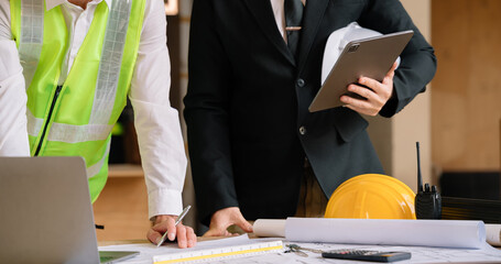 Businessman working as a team discussing data working and tablet, laptop with on on architectural project at construction site.