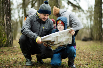 Naklejka na ściany i meble Father with son looking at map in the forest.