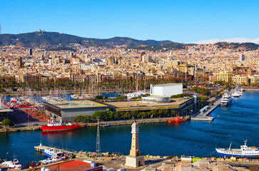 Picturesque aerial landscape view of Port Vell with moored yachts and ships in Barcelona. Downtown of Barcelona in the background. Travel and tourism concept. Cityscape at sunny day