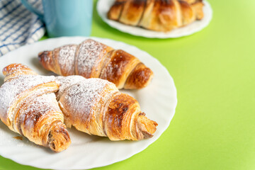 Close up of delicious chocolate croissants sprinkled with fine sugar. Sweet moment: croissants and coffee with chocolate. High quality photo