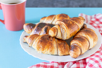 Group of delicious chocolate croissants with coffee cup on blue background. French breakfast: chocolate croissants and coffee on the table. High quality photo