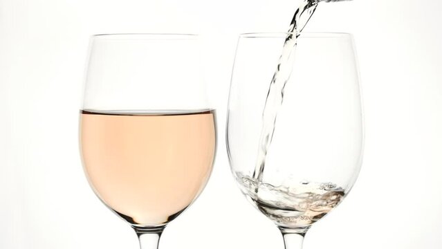 Pouring rose wine into glass from the bottle on the white background