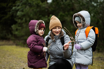 Mother with daughters holding willow twigs in forest.