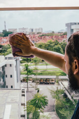 At home, clean the glass balcony. A man of Asian origin is cleaning his home.