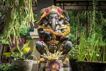 Ganesh Statue decorated with floweers in a temple in Ubud, Bali, Indonesia.