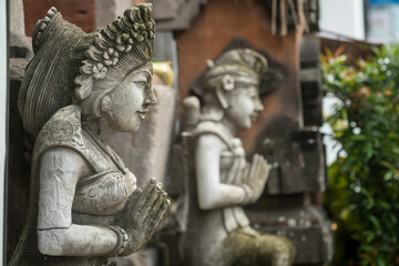 Stone statue with hands in a praying atthe temple' entrance on Bali, Indonesia.