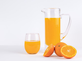 Freshly squeezed orange juice poured from a carafe into a glass with a cut orange on a white background, a refreshing vitamin drink, the concept of healthy and proper nutrition or diet