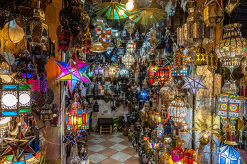 Colorful and golden chandeliers hanging in a shop in a souk in marrakech.