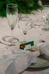 White napkin on a plate and a sign on the wedding table. empty glasses
