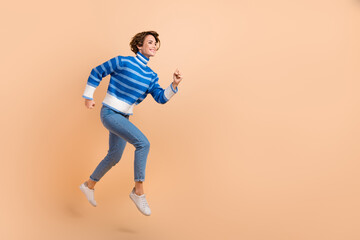 Fototapeta na wymiar Full body length photo of active running hurry woman fast speed motivation career empty space blue striped sweater isolated on beige color background