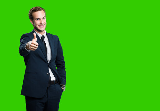 Excited businessman showing thumb up like sign gesture, in black confident style suit, green chroma key background. Handsome happy man. Copy space for slogan or text.