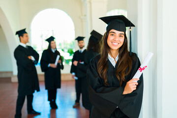 Portrait of an attractive graduate smiling with her college diploma