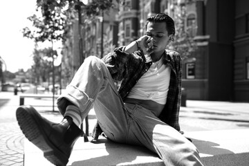 Pensive guy sitting on stone bench in sunny tow square