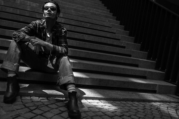 Relaxed confident guy posing on stone stairs on city street - obrazy, fototapety, plakaty