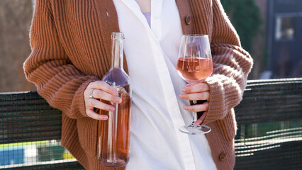 woman with a glass of wine, bottle of rosé, outside on a balcony