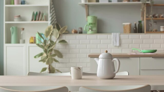 No people shot of bright cozy kitchen interior with white furniture and teapot with cup on table