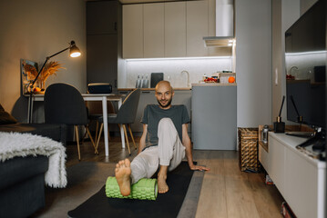 Sport and healthy lifestyle concept - smiling man exercising and stretching at home