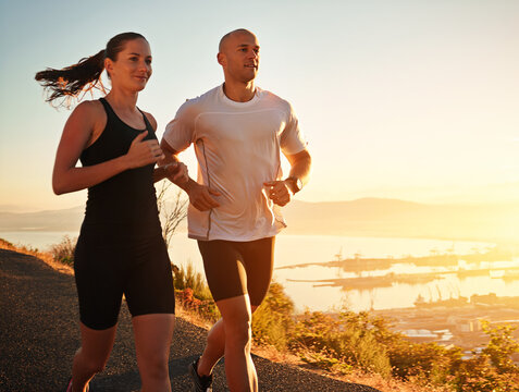 Running is part of their daily routine. Shot of a young couple running together along a road.