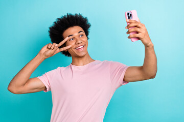 Photo of youngster blogger guy hold smartphone show v-sign friendly person recording video broadcast selfie isolated on aquamarine color background