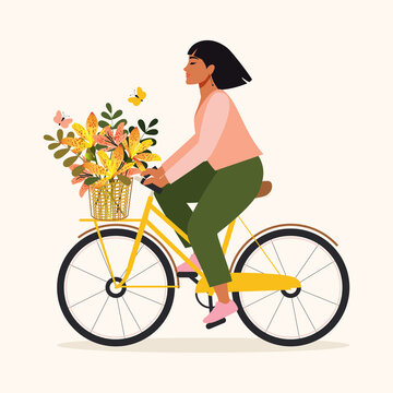 A happy woman with a bouquet of leopard flowers in a basket rides a bicycle and rejoices at the beginning of spring. Cute girl enjoying warm weather, doing physical and mental health. 