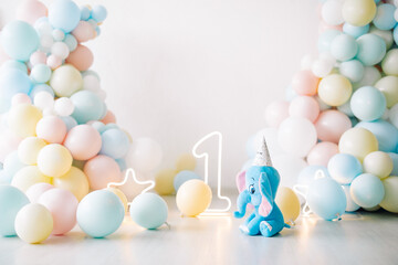 Decoration for a first birthday party with lot of colorful balloons, stars, numeral one and toy elephant.