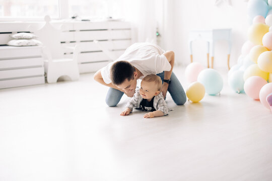 Happy father plays with his son celebrating first birthday of baby boy .