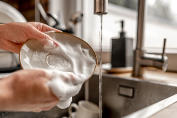 Girl washing dishes at kitchen at home
