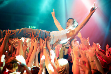 A young man cheering as he crowd surfs at a concert. This concert was created for the sole purpose...