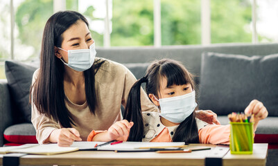 Portrait happy love asian family mother teach little daughter asian girl learn and study on table.Mom and asian young girl writing with book and pencil making lessons in homeschool at home.Education