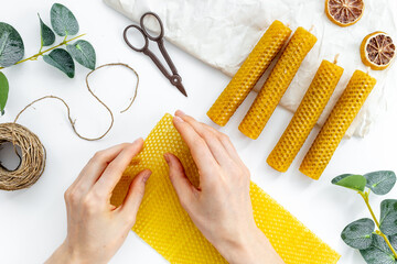 Hands making beeswax honey aroma candles with honeycombs, top view - obrazy, fototapety, plakaty