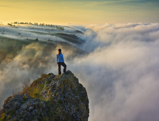 young woman stands on a rock above a river canyon. female tourist enjoys foggy autumn landscape. nature of Ukraine