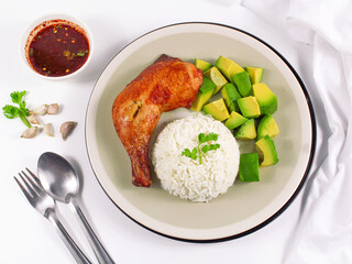 Grilled chicken on white plate with avocado and rice.