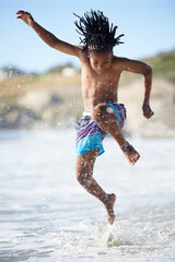 Splash. An excited young boy leaping into the air while at the beach.
