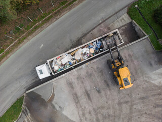 Skid steer loader loading a truck with waste material transferred for further sorting, treatment,...