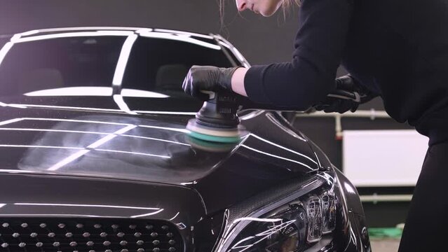 Worker polish a black car. Car detailing - woman are using machinery car polishers maintenance to remove marks repair according to the surface of the car's paint before contin