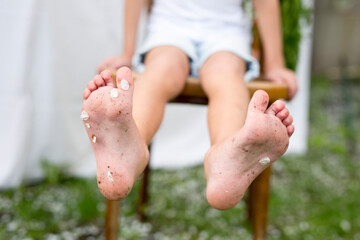 Bare children's feet in the garden are soiled with dirt and cherry petals