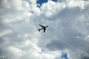 Long-distance shot of a plane directly below him, blue sky with clouds in the background.