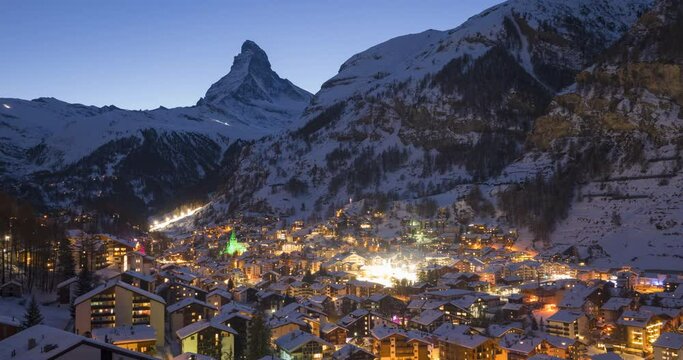 4K Time lapse of Zermatt city Valley famous travel ski resort and iconic Matterhorn peak at dawn in Swiss alps, Switzerland. The snow covered village and church in Canton Valais in winter Timelapse.